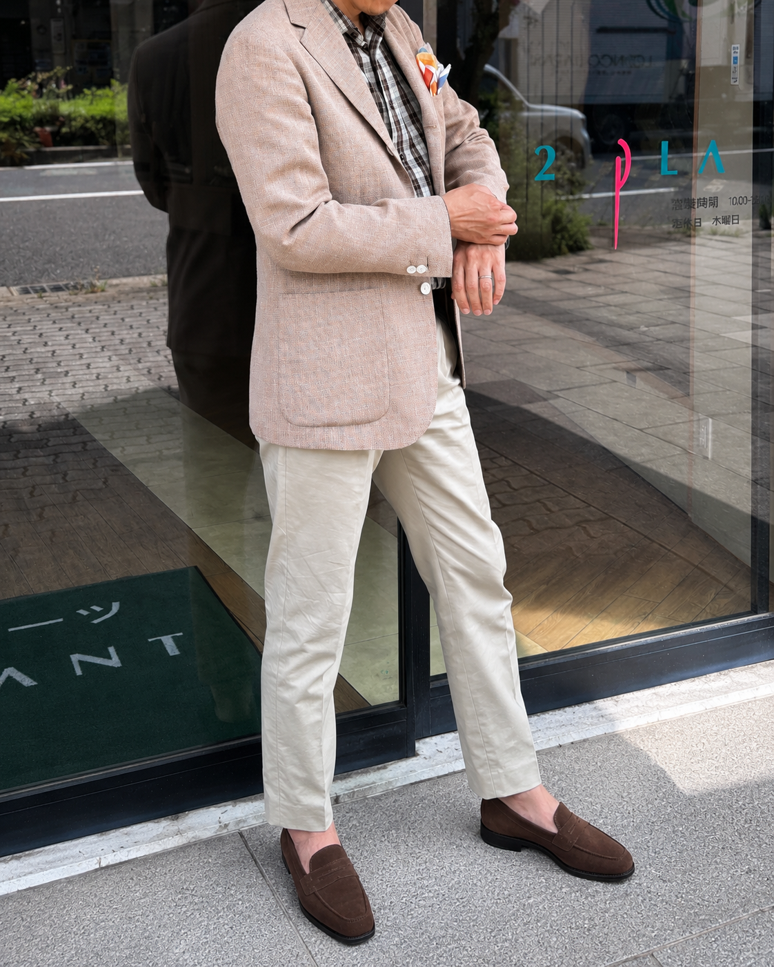 ベージュジャケットと明るいパンツを合わせた屋外コーディネート