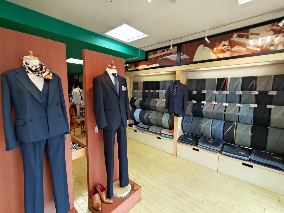 M2PLANTくずは並木店のスーツと生地が並ぶ店内